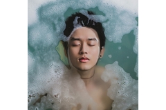 Image A birds-eye view of an Asian man's face coming out of water with bubbles surrounding him.